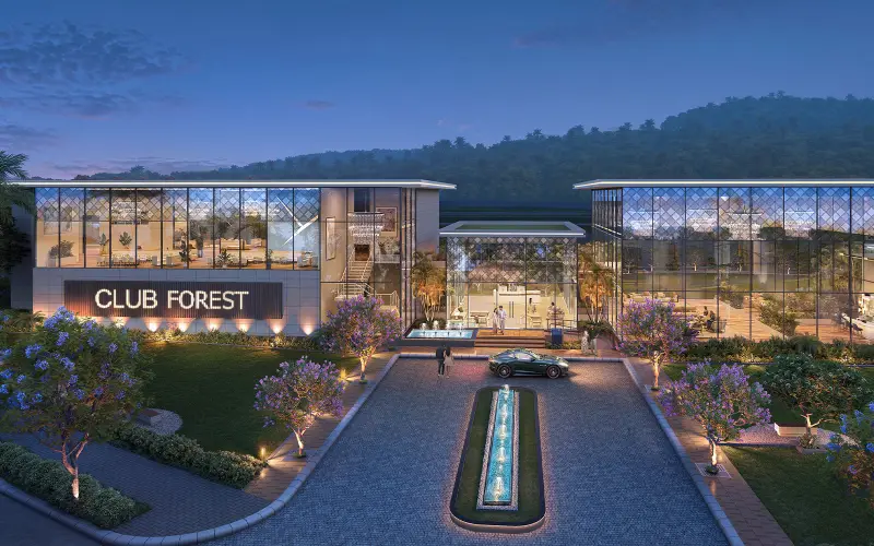 Club Forest, the clubhouse, lit up at dusk with a fountain drive